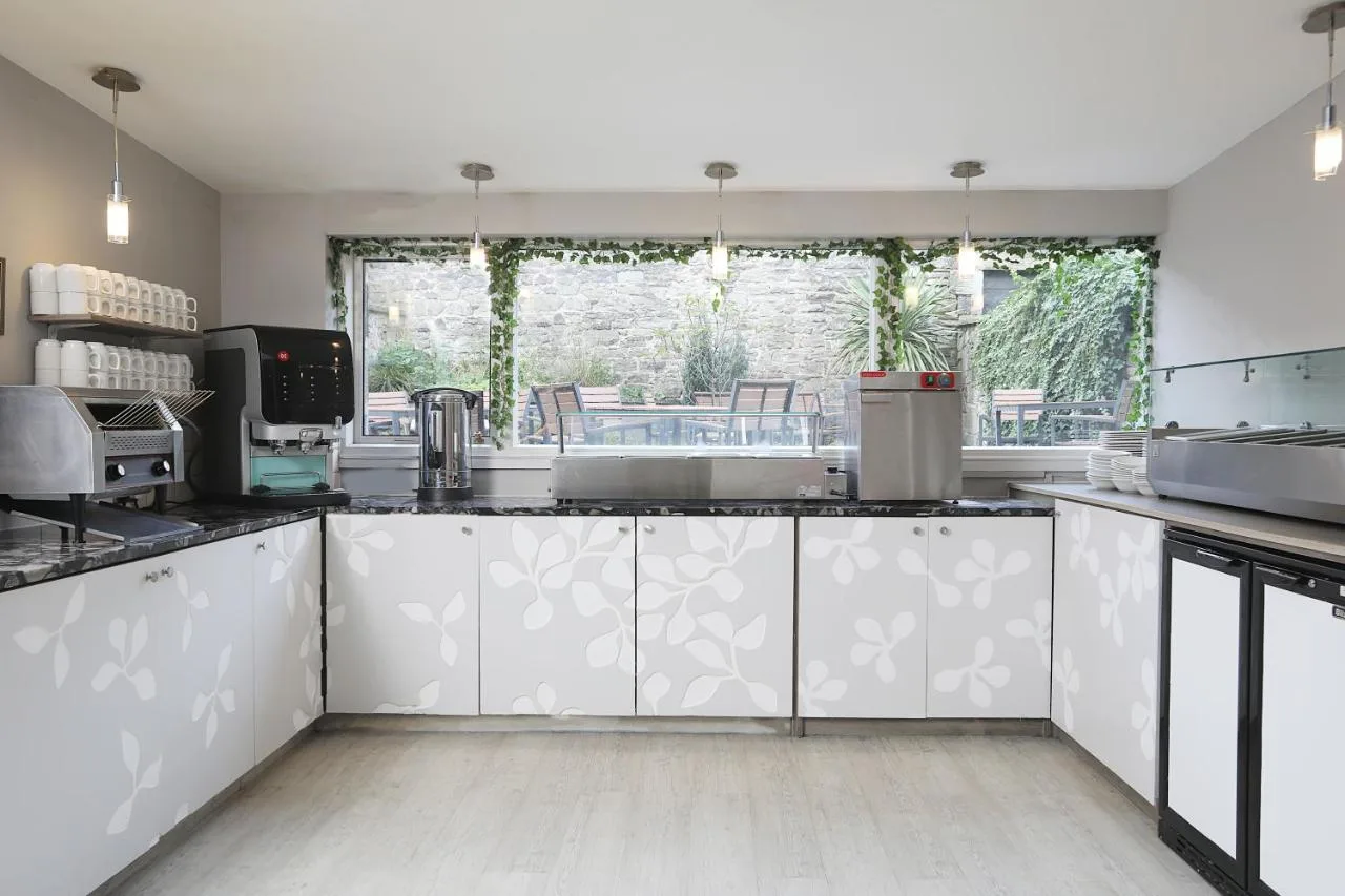 a kitchen with white cabinets and a large window at Cairn Hotel & Apartments in Edinburgh