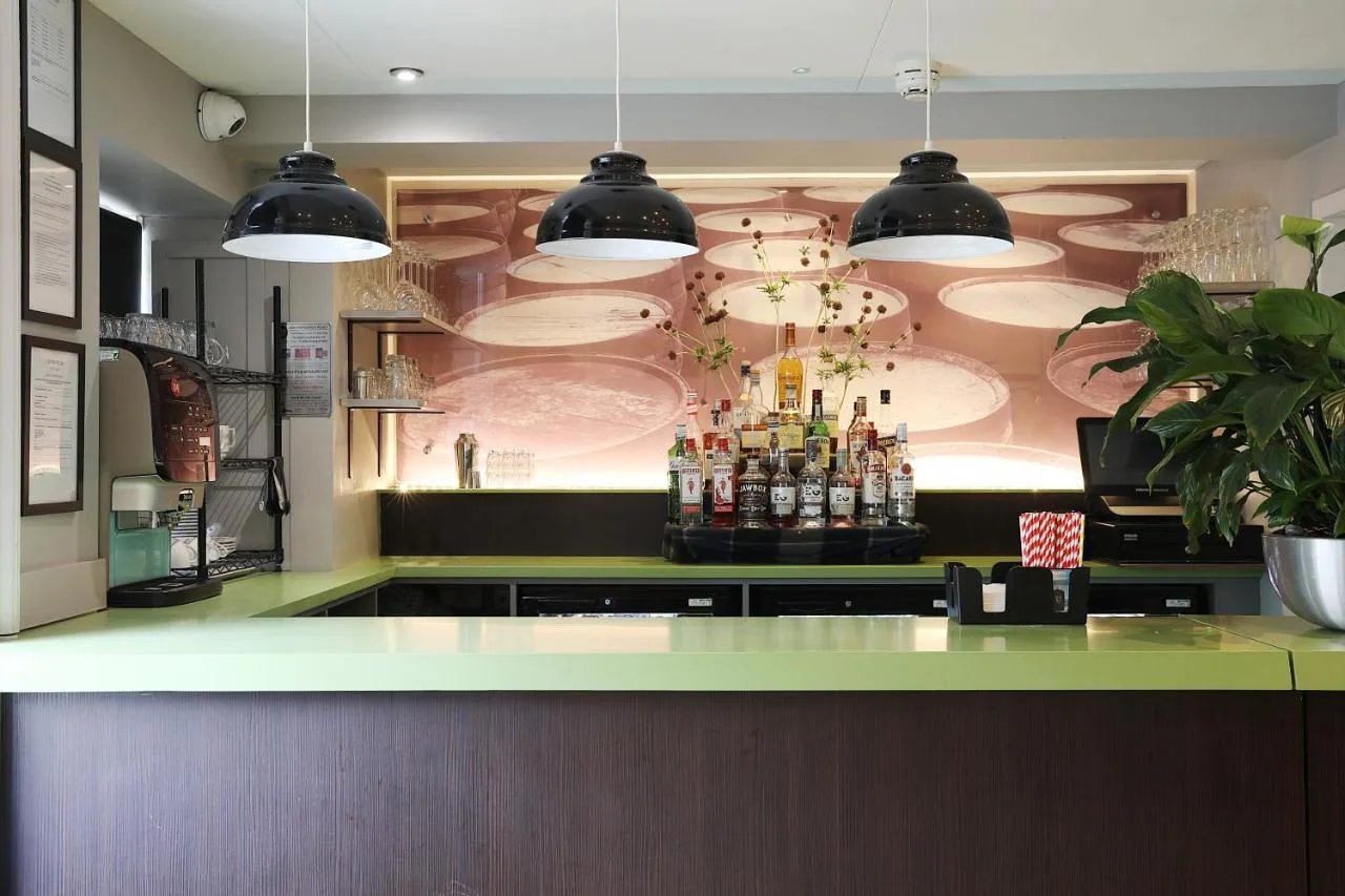 a bar in a restaurant with a wall of plates at Cairn Hotel & Apartments in Edinburgh