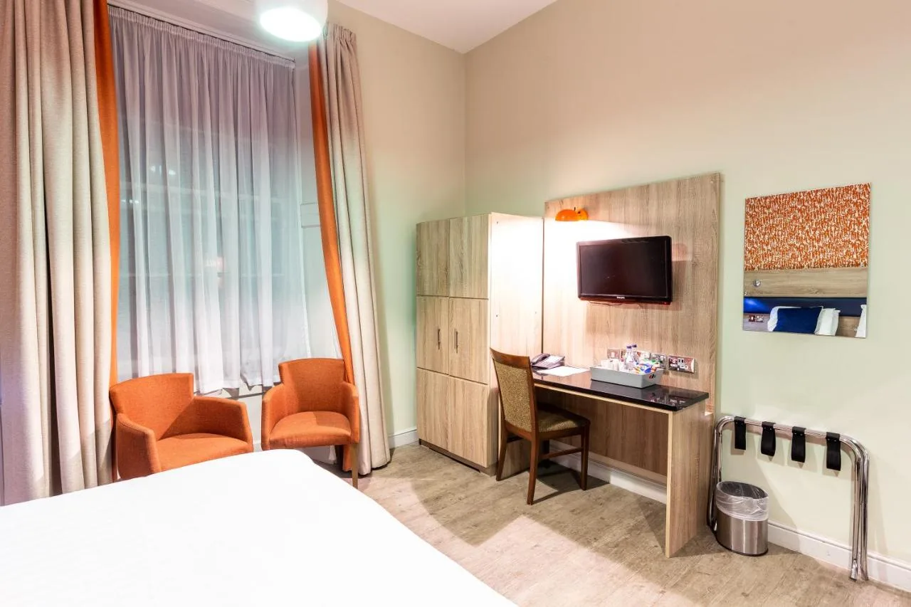 a hotel room with a bed and a desk and a tv at Cairn Hotel & Apartments in Edinburgh